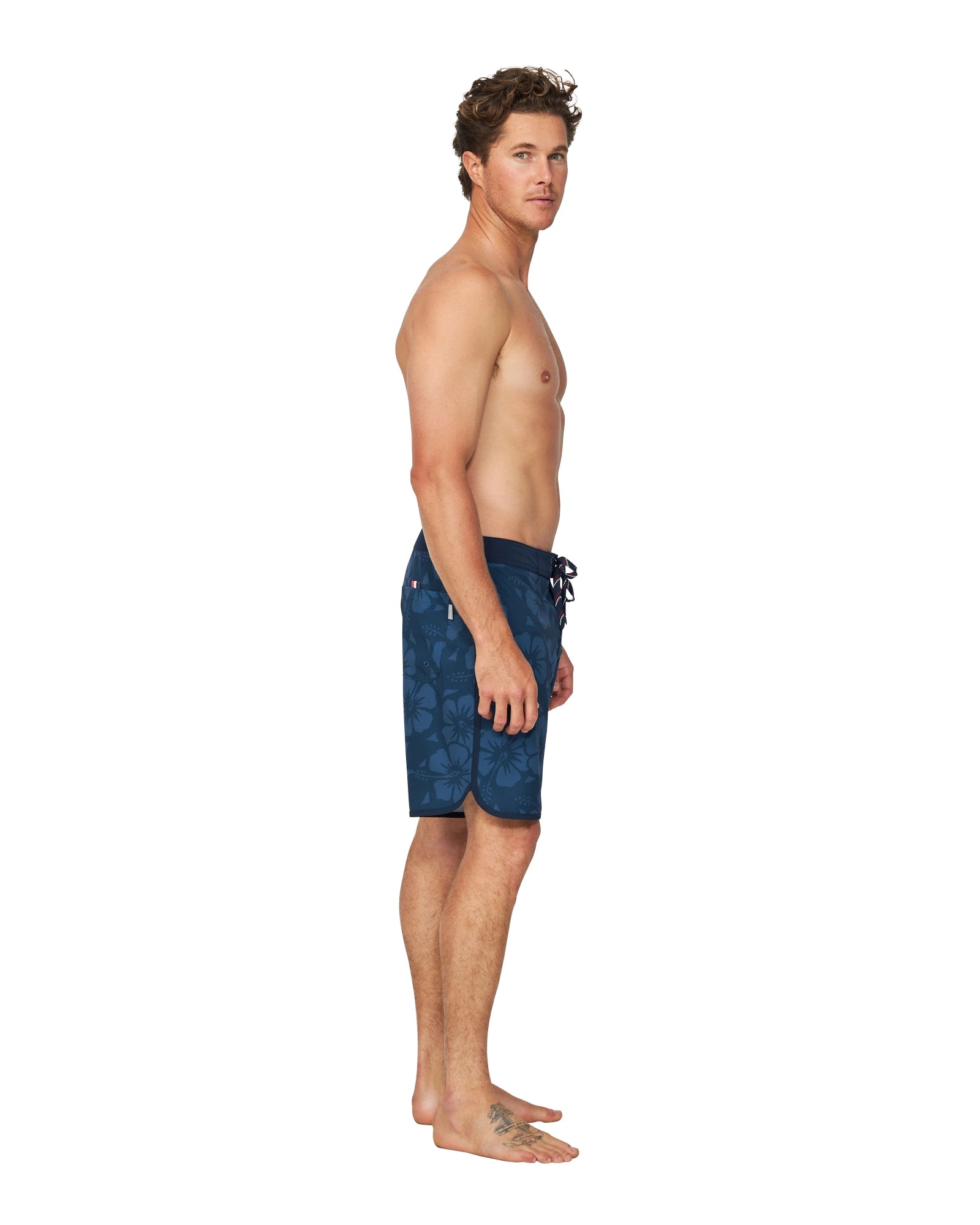 A side-view of a male model wearing the Okanui Boardrider Boardshorts.