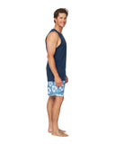 A side view of a smiling male model wearing the Okanui Classic Badge Tank Top for men in navy colour and a hibiscus swim shorts.