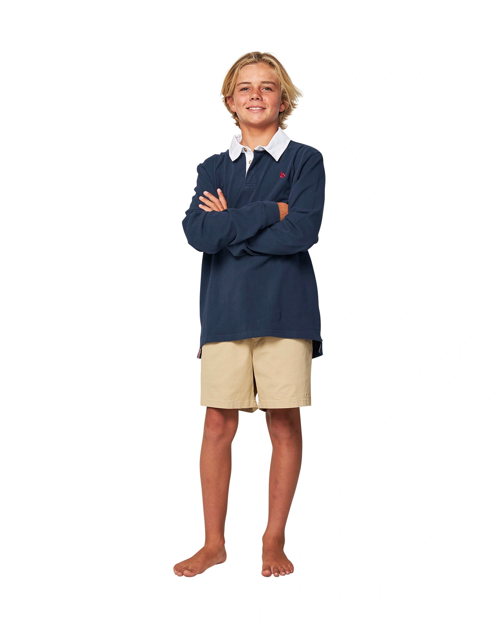 Full body front view of a boy with a cross-arm pose wearing the Okanui Heritage long sleeve rugby tops and jumpers in Navy