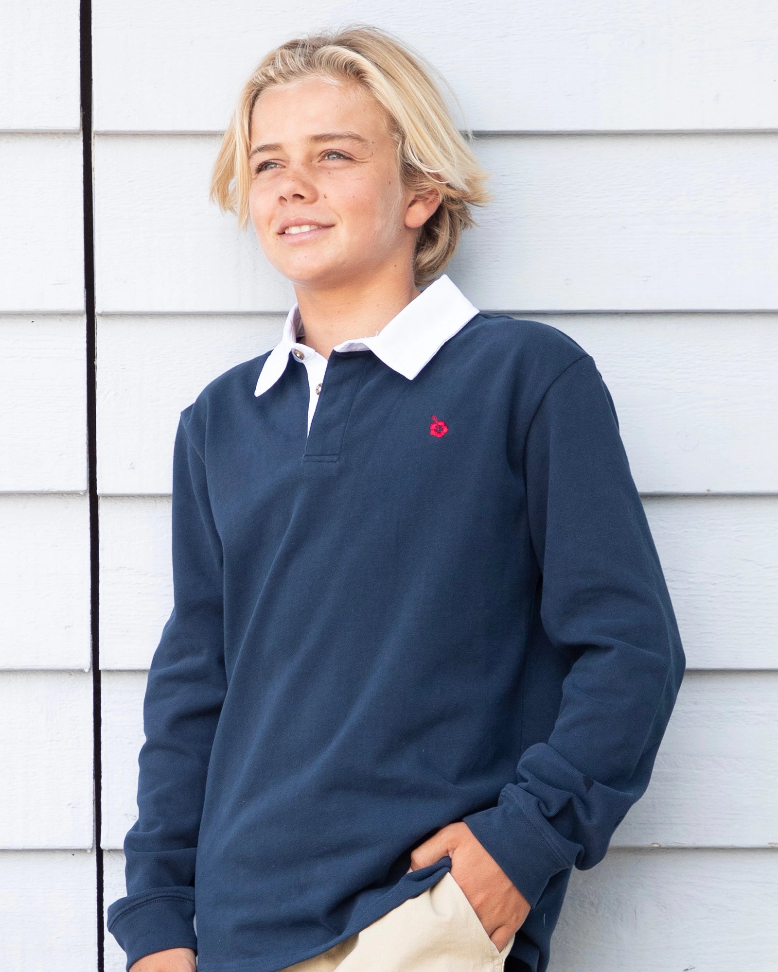 Closeup front view of a boy with his hand in his pocket, wearing the Okanui Heritage long sleeve rugby tops and jumpers in Navy