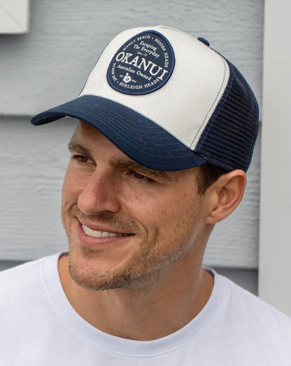 A male model wearing the Okanui  trucker cap mesh back in Navy Natural color