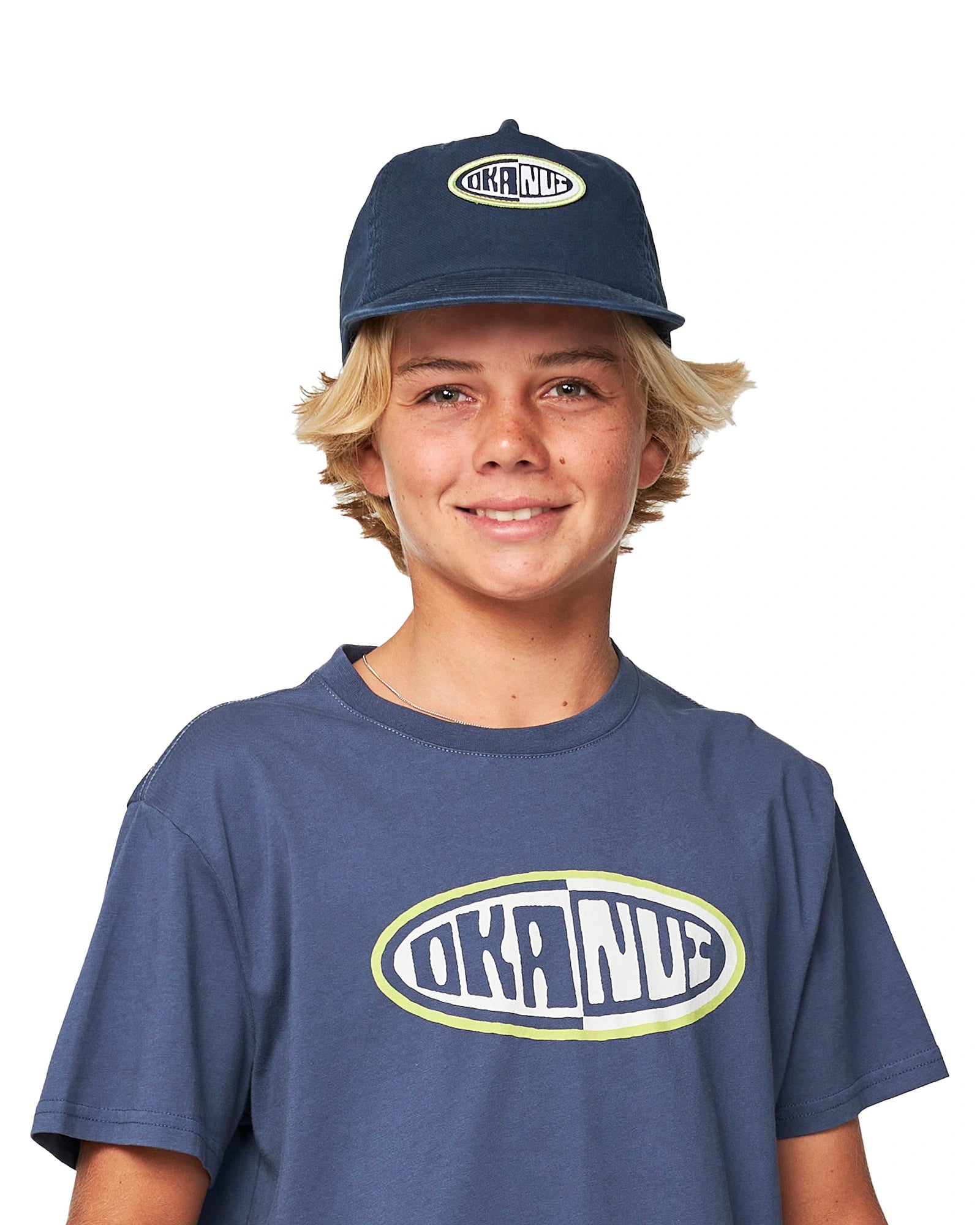 Front view of a boy wearing the Washed Navy Okanui Deck Kids snapback trucker cap