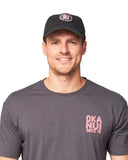 Male model wearing a short sleeves shirt and black Okanui trucker cap