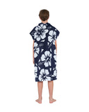 Back view of a boy with its hood off wearing the Okanui Hooded Towel in Hibiscus Navy color
