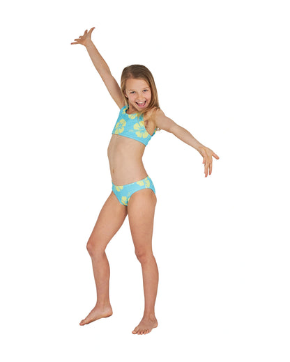 A joyful pose of a girl wearing the Okanui crop bikini set in Hibiscus Aqua Yellow