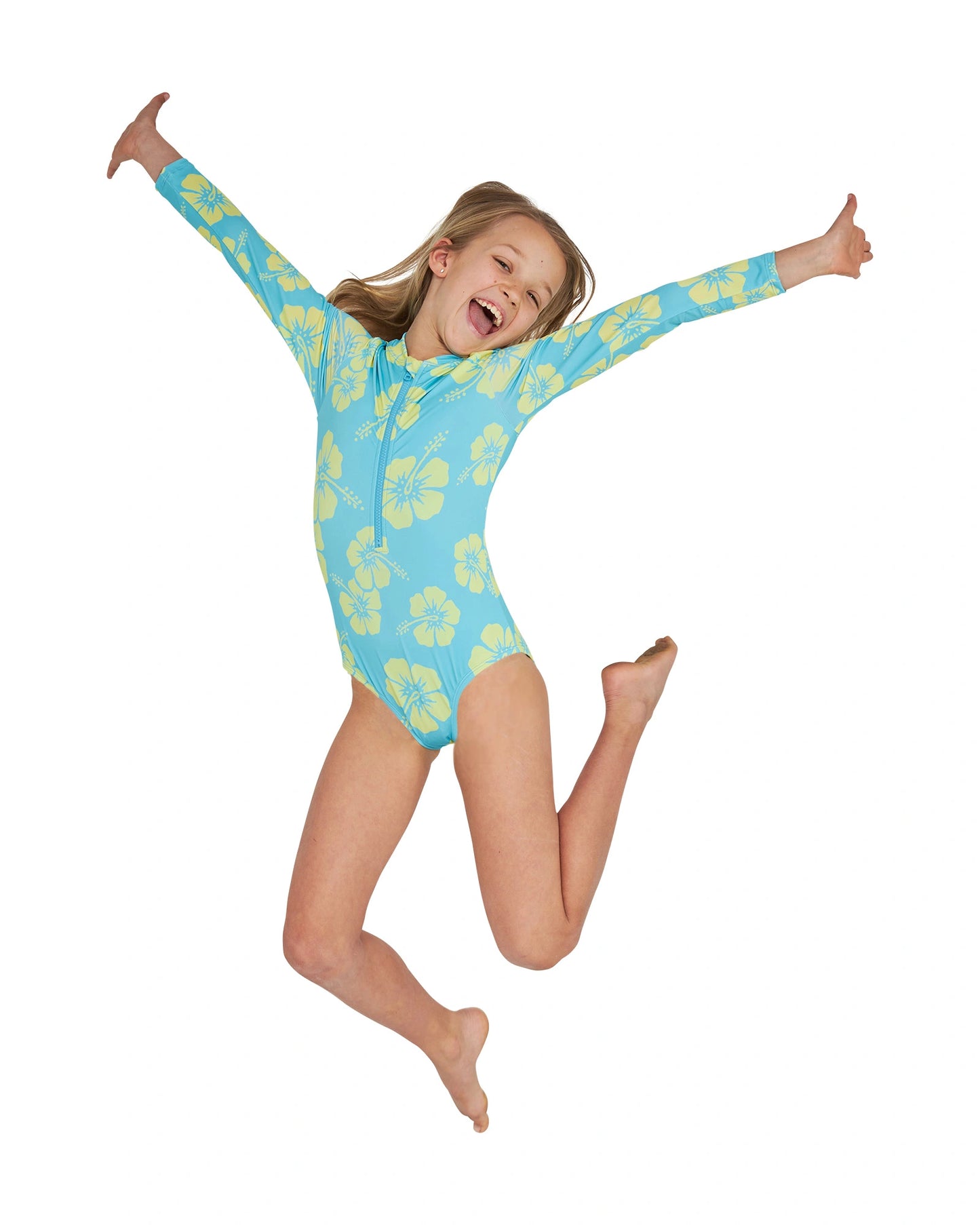 A jumping girl with her hands widespread wearing the Okanui long sleeve one piece swimsuit for girls in Hibiscus Aqua Yellow