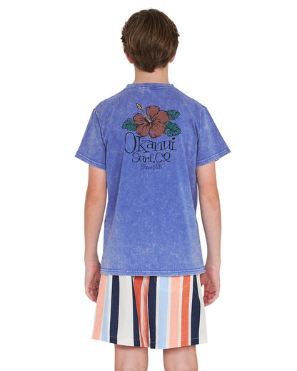 Back view of a boy wearing a blue shirt paired with the Okanui stretch swim shorts in Birch Multi