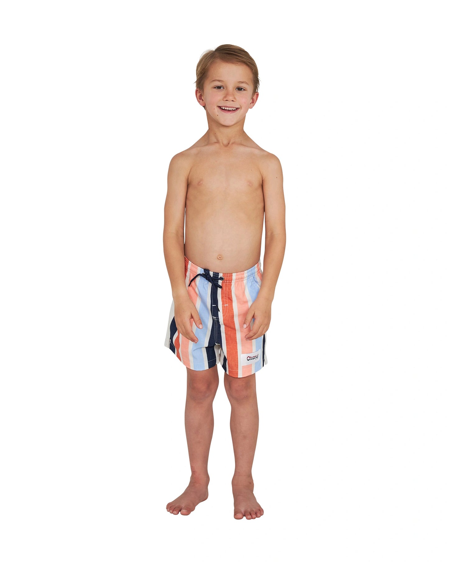 Full body front view of a topless boy wearing the Okanui stretch swim shorts in Birch Multi