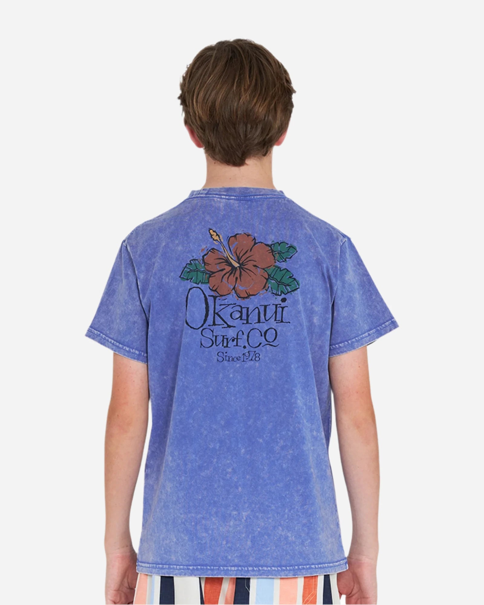 Back view of a boy wearing the Okanui Good Company Tee T-shirt in Washed Blue