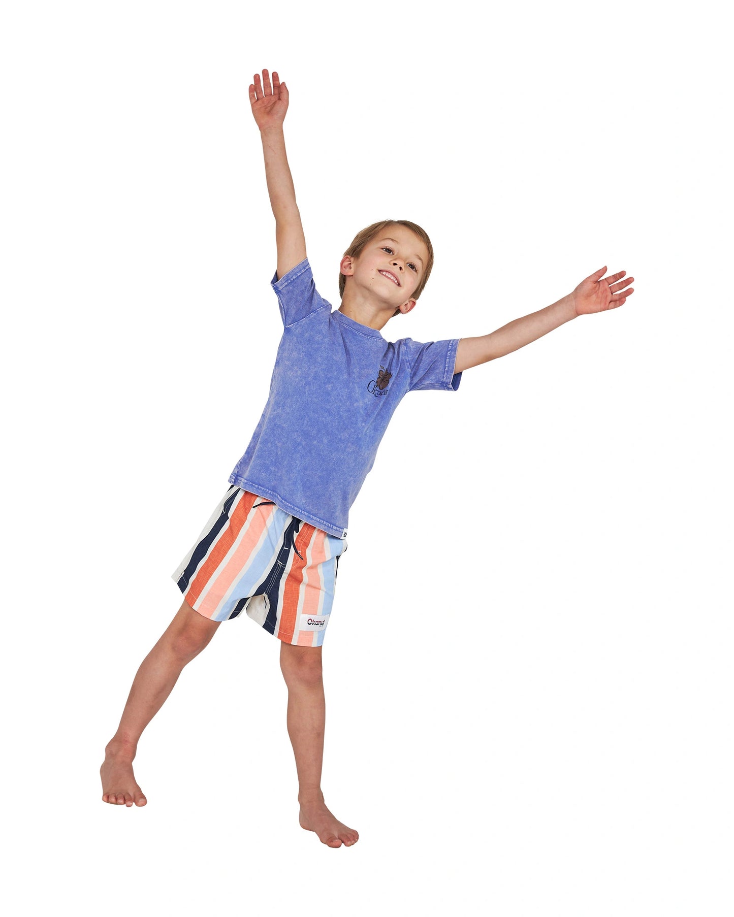 Joyful pose of a little boy wearing the Okanui Good Company Tee T-shirt in Washed Blue