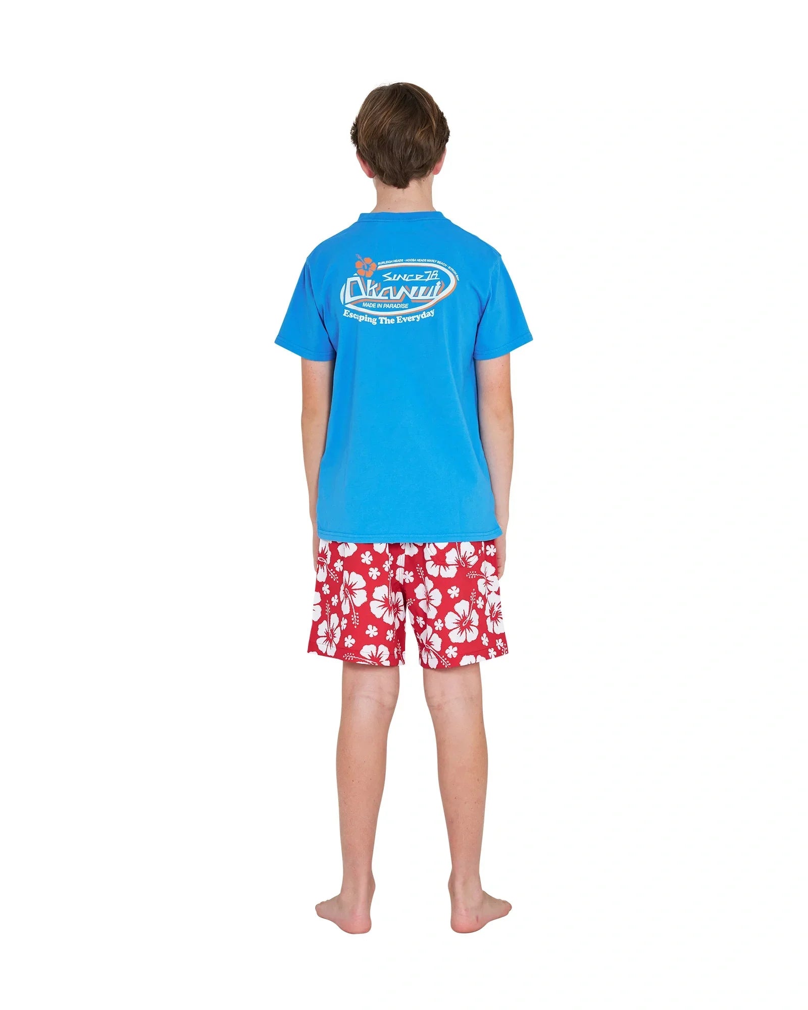 Full body back view of a boy wearing the Okanui Point Break Tee T-shirt in Washed Blue