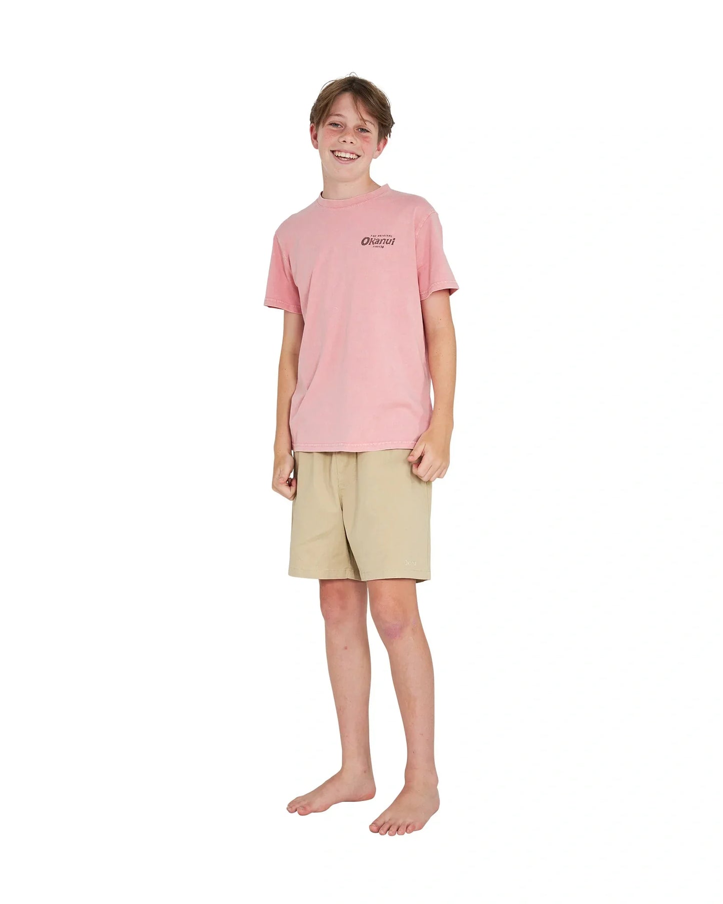 Full body front view of a boy wearing the Okanui boys terrain Tee T-shirt in Washed Pink