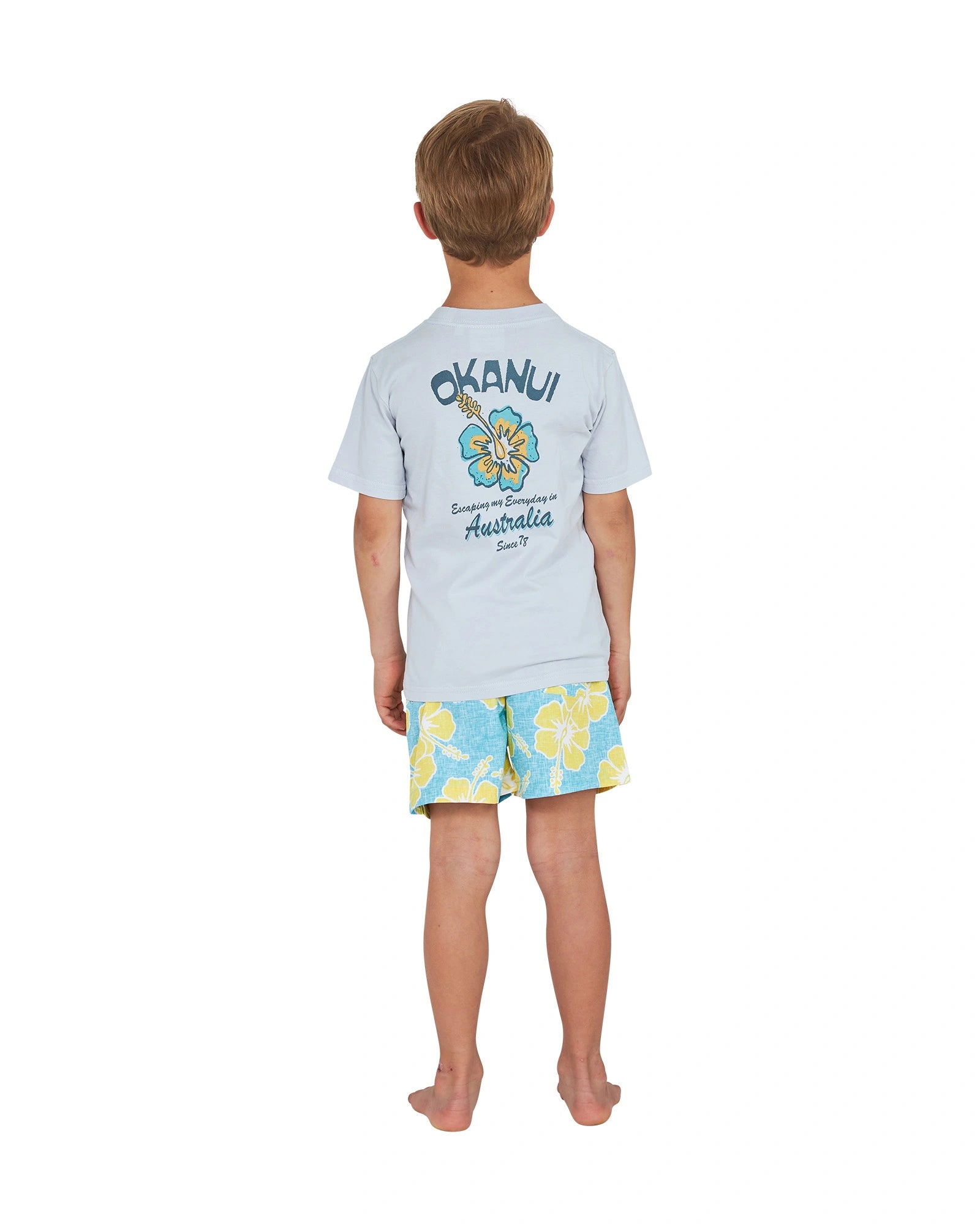 Full body back view of a little boy wearing the Okanui Way Back When stretch swim short in Aqua yellow