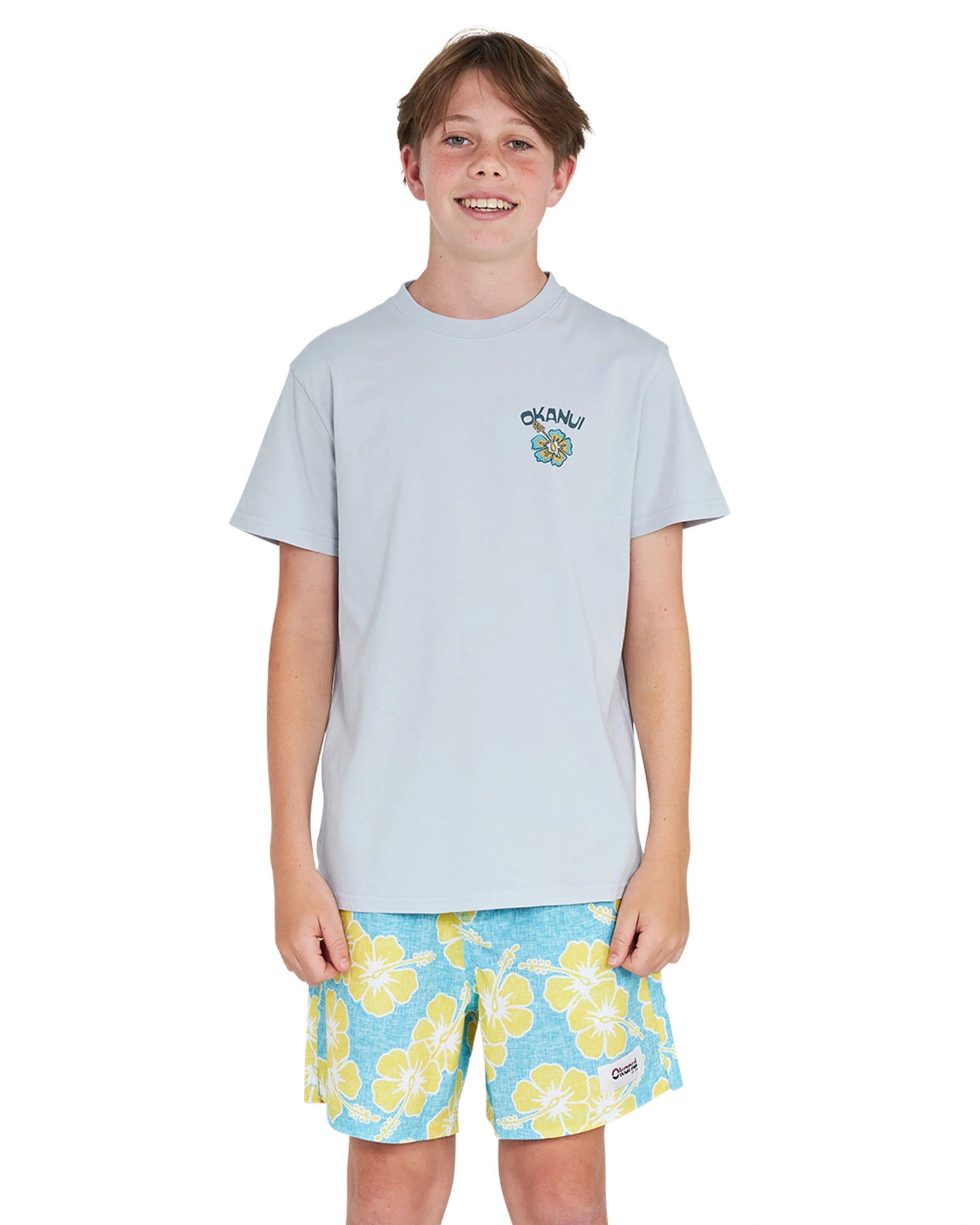 Full body front view of a boy in white tshirt paired with the Okanui Way Back When stretch swim short in Aqua yellow