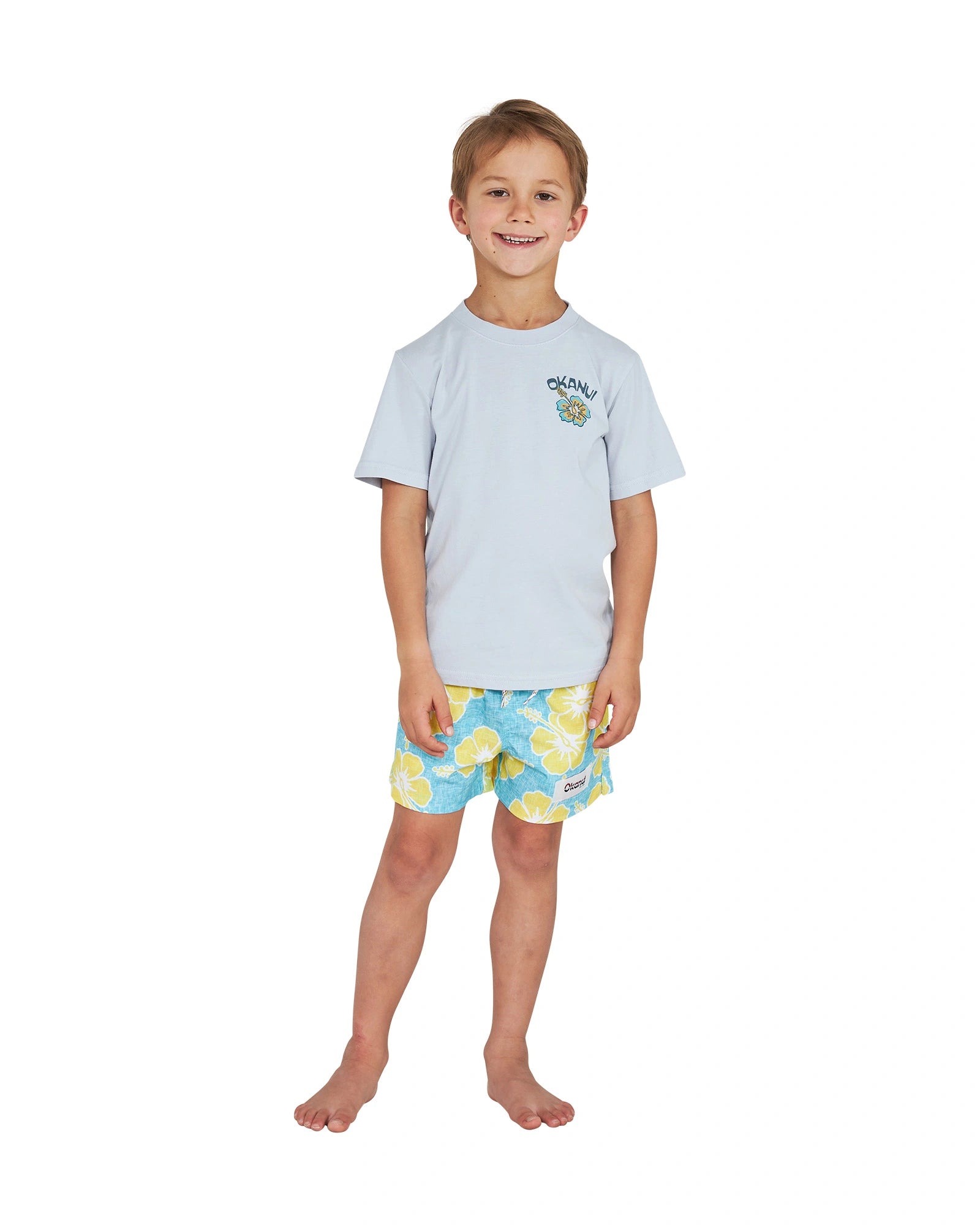 Full body front view of a little boy wearing the Okanui Way Back When stretch swim short in Aqua yellow