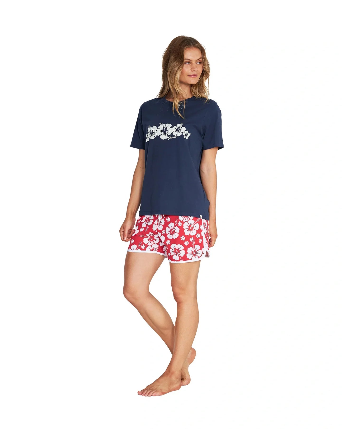 Full body angled front view of a female model wearing the Okanui Inline cotton T-shirt in Navy color