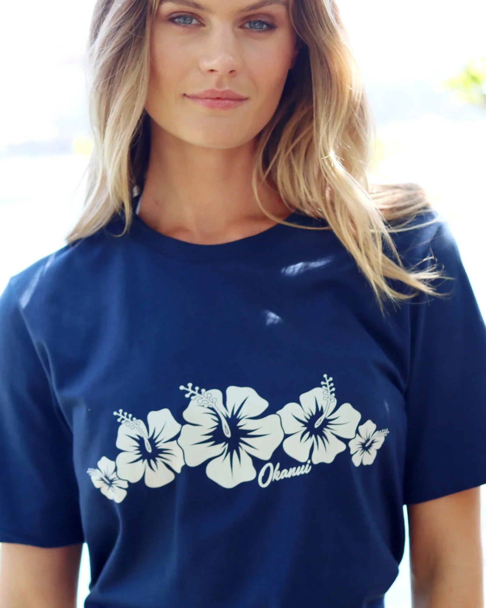 Close up front view of a female model wearing the Okanui Inline cotton T-shirt in Navy color