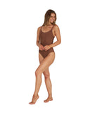 A woman wearing a reversable brown one-piece showing the side details. 