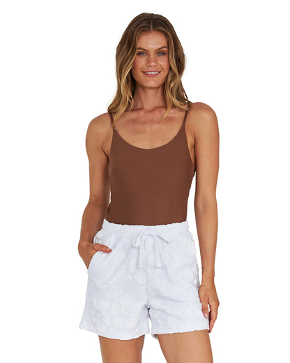 A woman wearing a brown top and a white terry short.