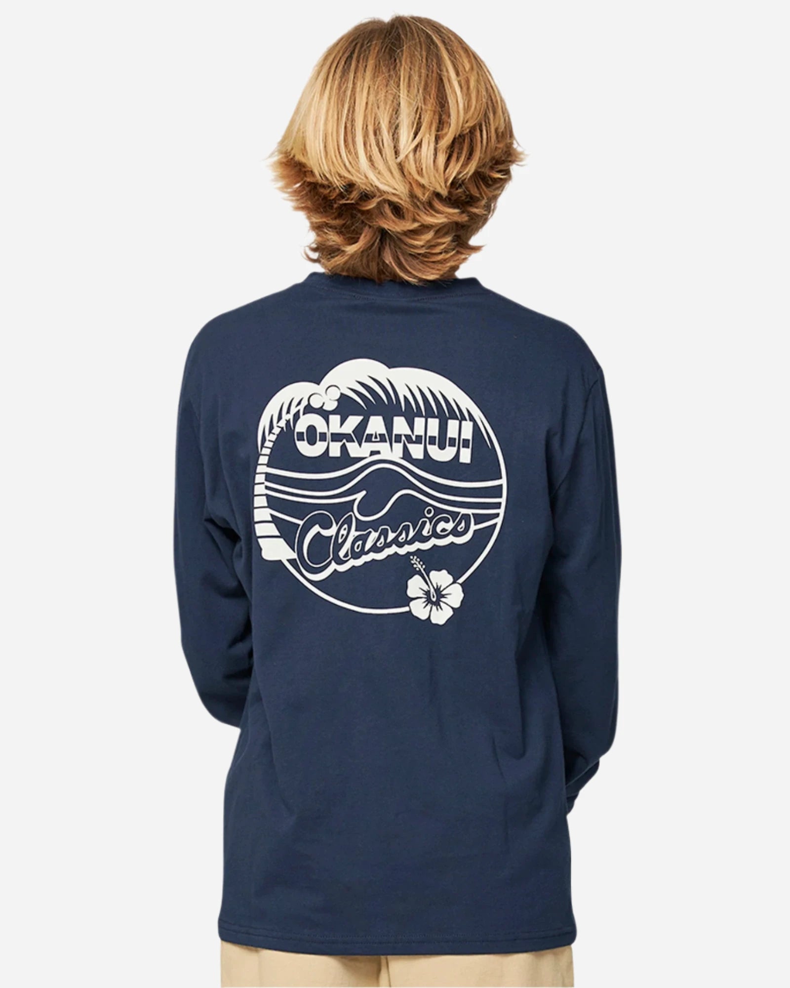 Closeup back view of a boy wearing the Okanui classic badge long sleeve T-shirt in Navy