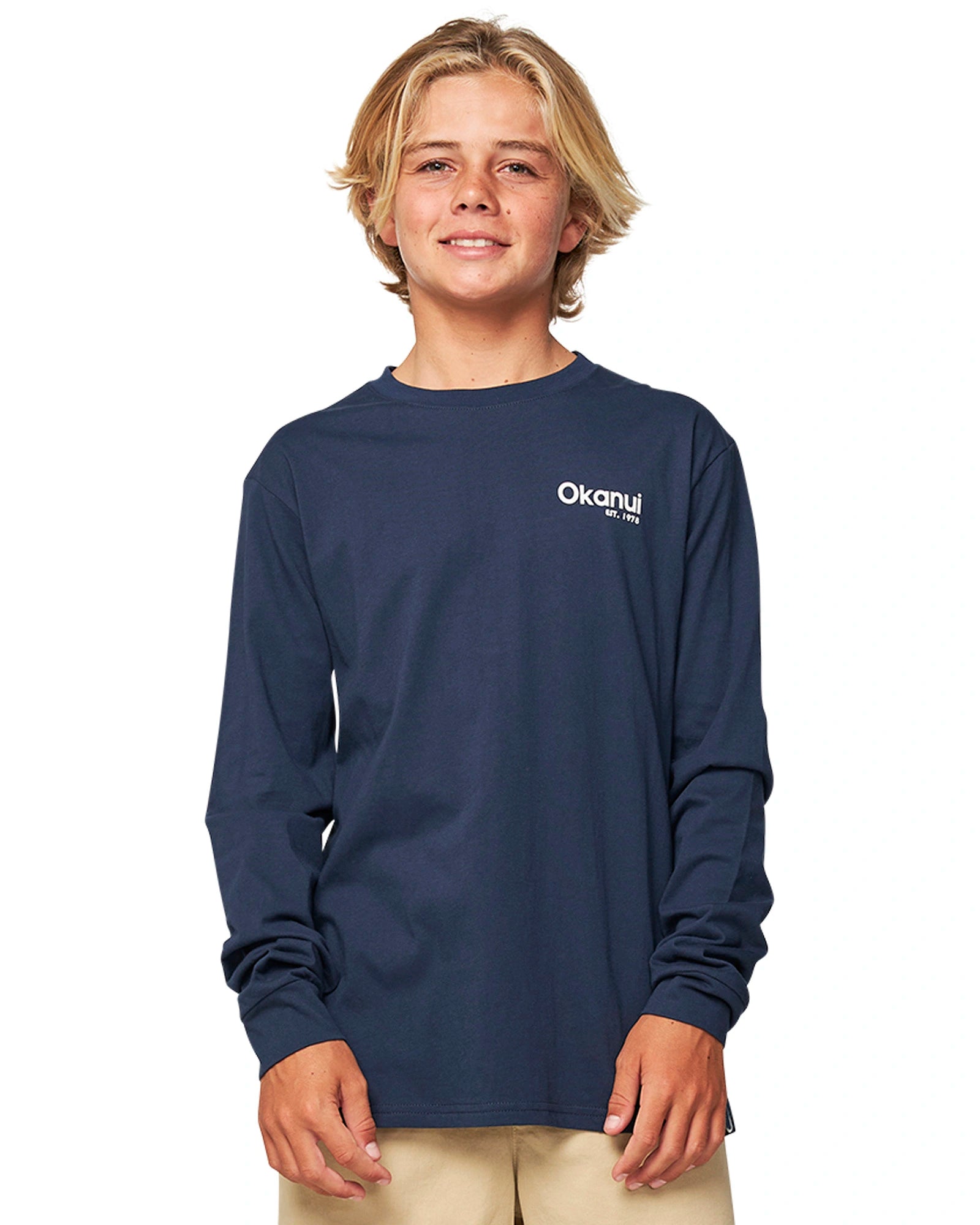 Closeup front view of a boy wearing the Okanui classic badge long sleeve T-shirt in Navy