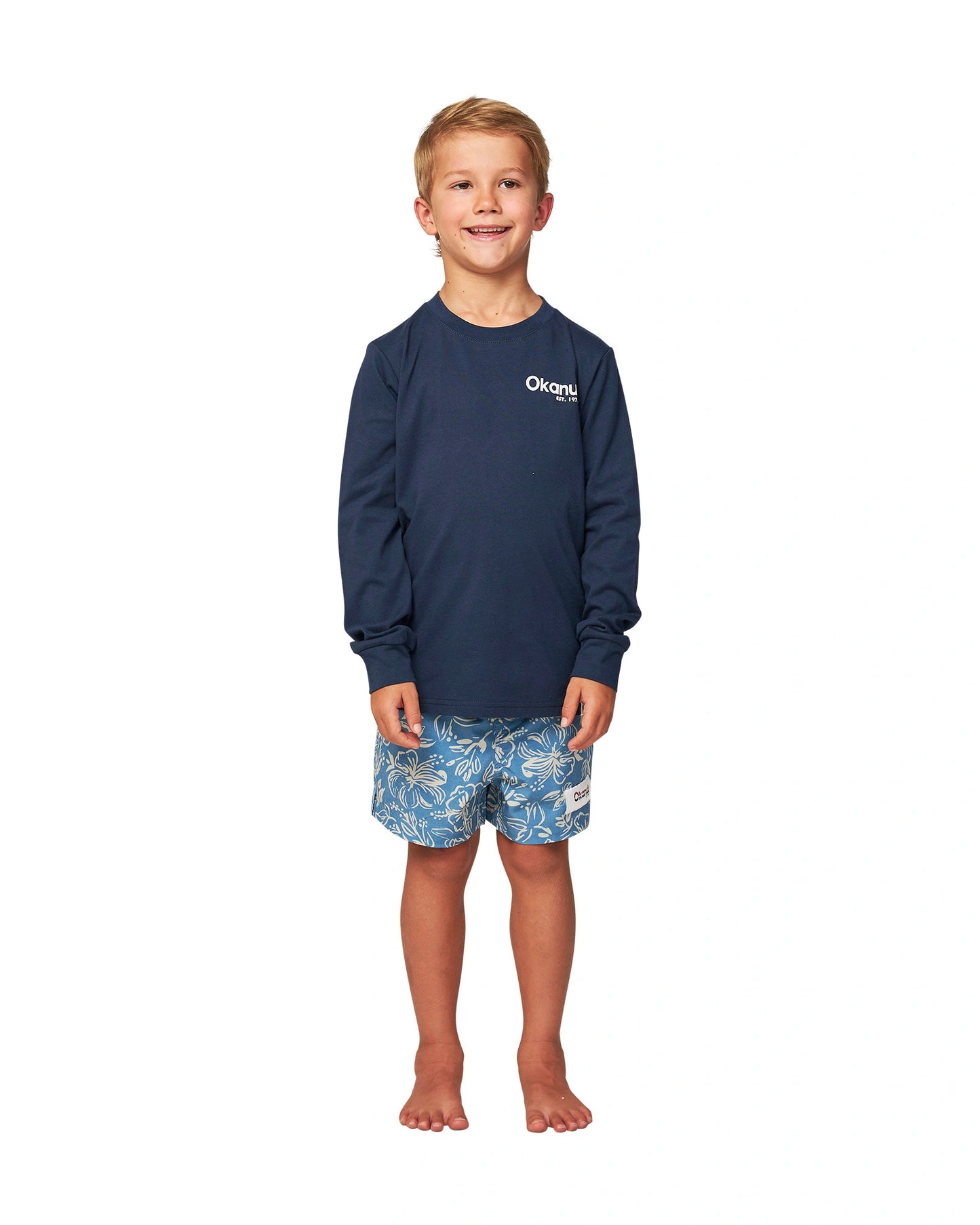 Full body front view of a little boy wearing the Okanui classic badge long sleeve T-shirt in Navy