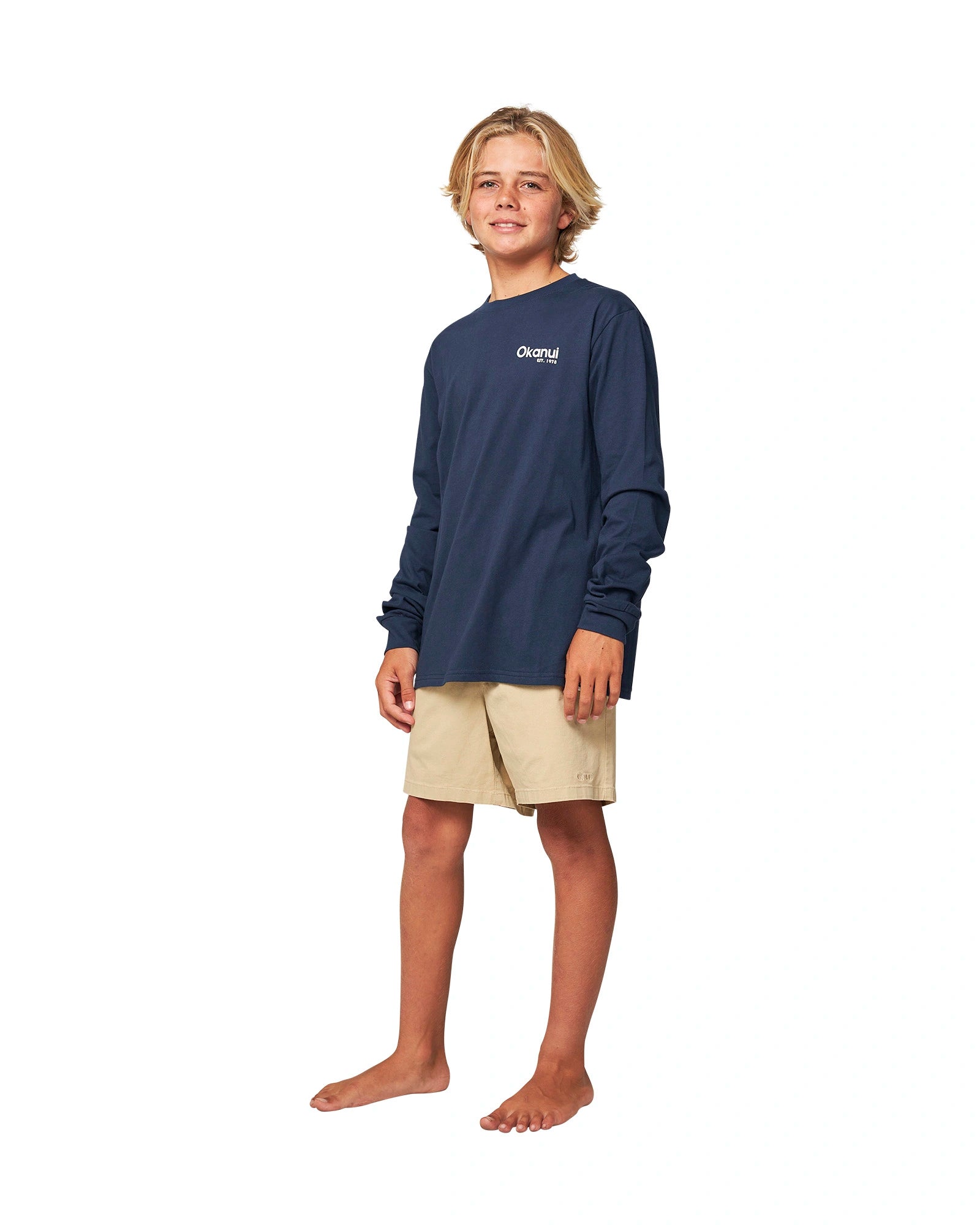 Full body front view of a boy wearing the Okanui classic badge long sleeve T-shirt in Navy