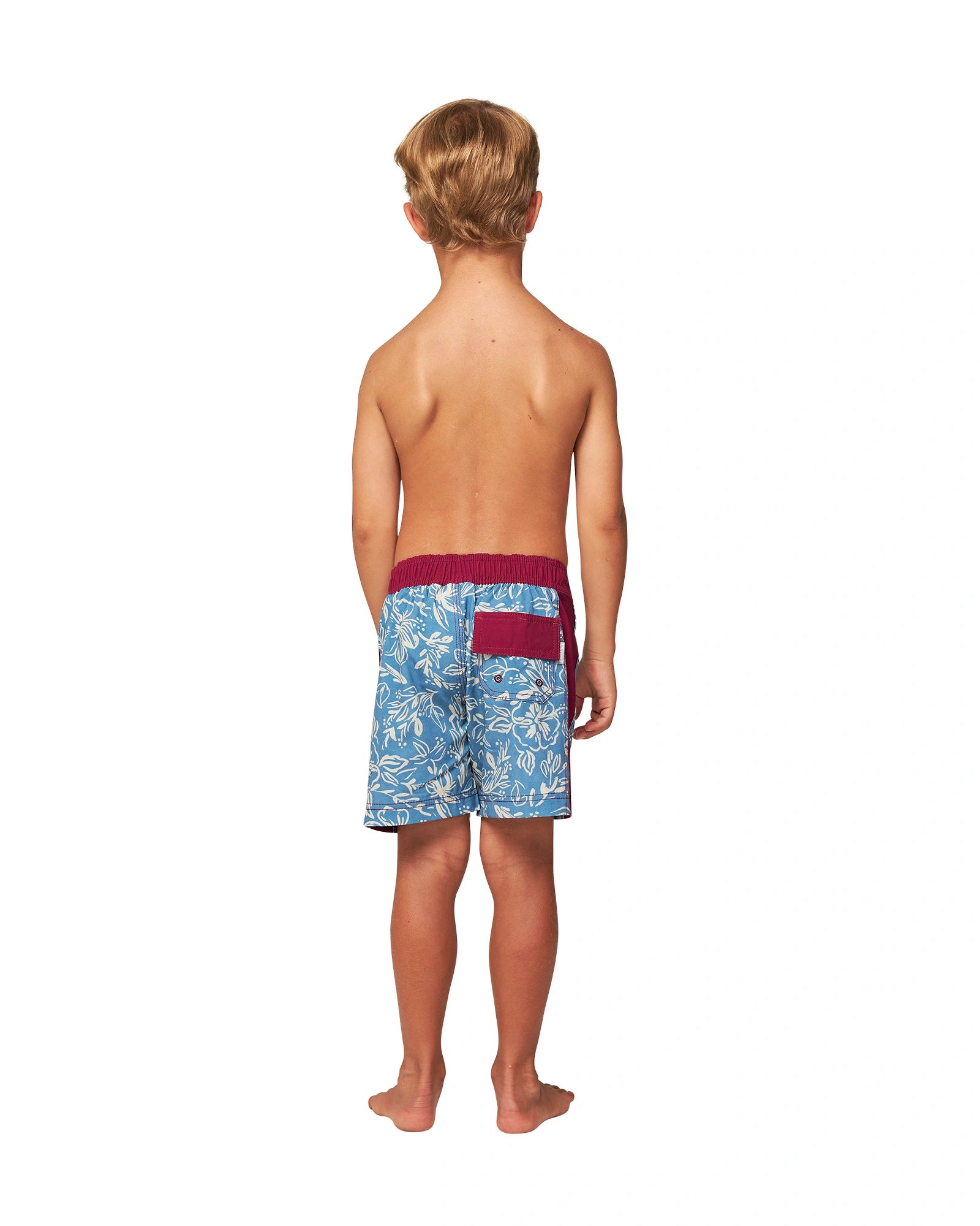 Full body back view of a topless little boy wearing the Okanui Kids swim shorts in Steel