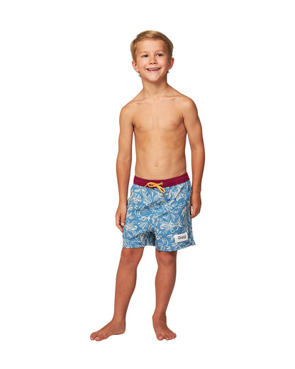 Full body front view of a topless little boy wearing the Okanui Kids swim shorts in Steel