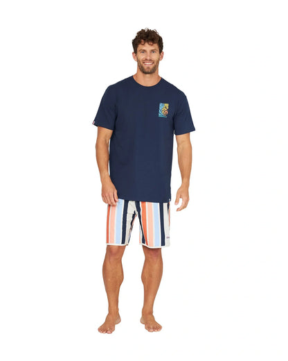A male model wearing a navy shirt and the Okanui Above Board Retro Boardrider Boardshort in Birch Multi.