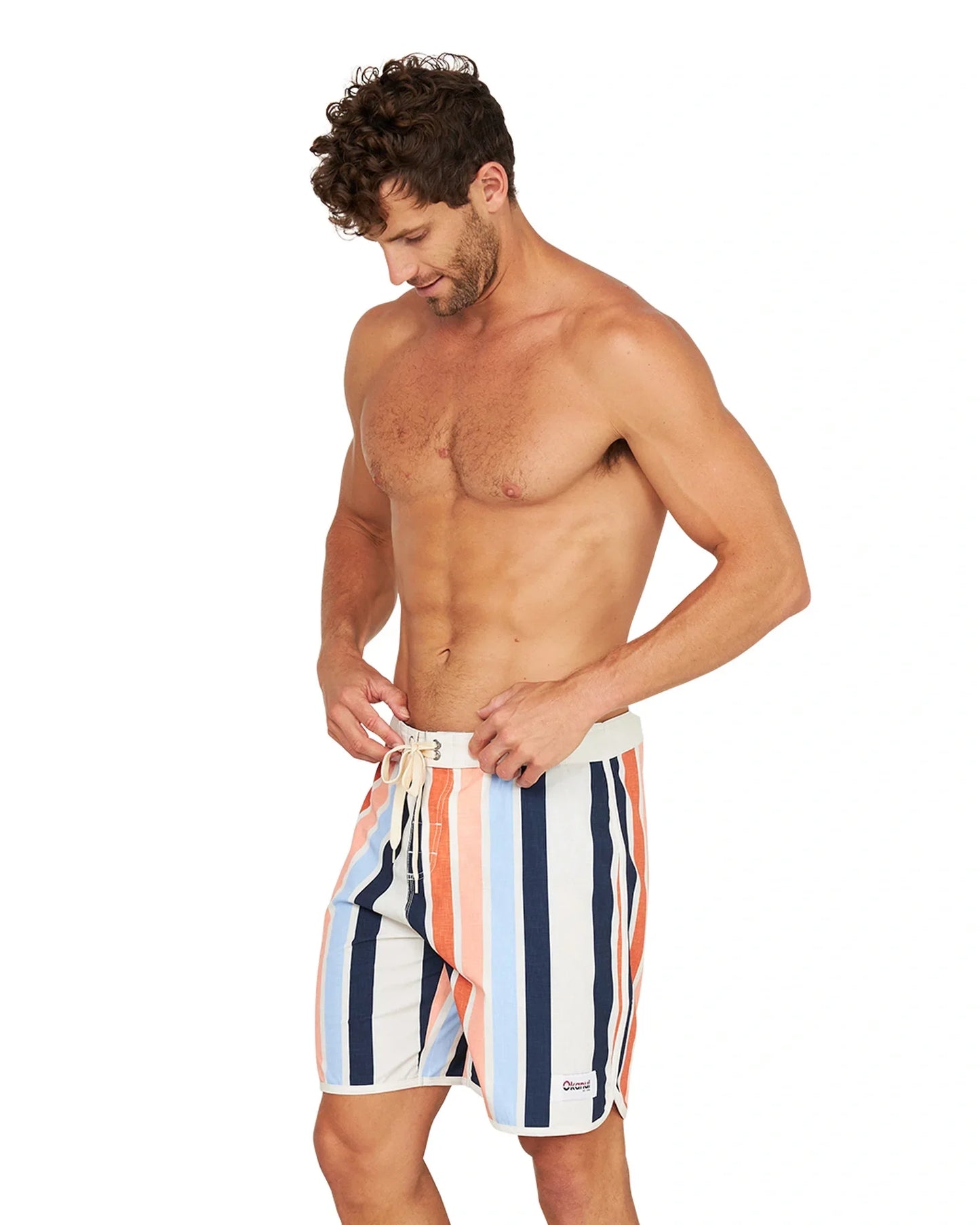 A shirtless male model wearing the Okanui Above Board Retro Boardrider Boardshort in Birch Multi.