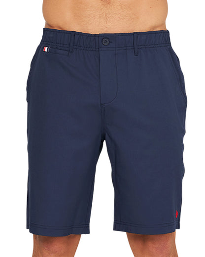 A lower close up front view of a male model wearing the Okanui Active Byrd Golf Shorts in navy color.