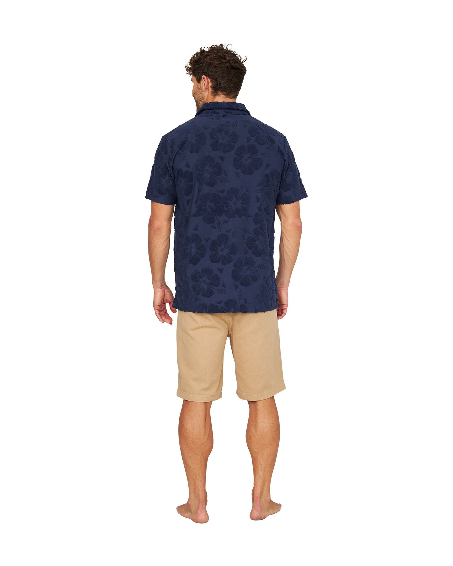 A full body back view of a male model wearing the Okanui Dockside Walk Short in sand color.