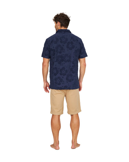 A full body back view of a male model wearing the Okanui Dockside Walk Short in sand color.