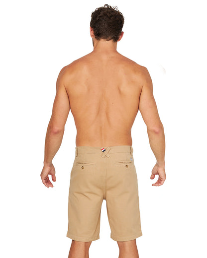 A full body back view of a shirtless male model wearing the Okanui Dockside Walk Short in Sand.