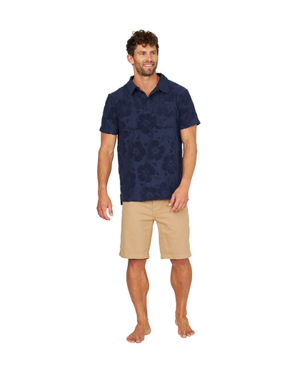 A full body view of a male model wearing the Okanui Dockside Walk Short in sand color.