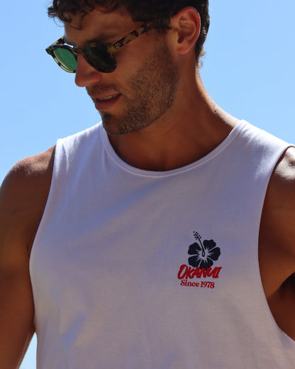 A close up view of a male model featuring the chest logo of the Okanui Origins Tank in fresh White.