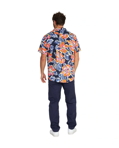 Full body back view of a male model wearing the Okanui Rhapsody Aloha Short Sleeve Shirt in navy multi, navy pants and white shoes.