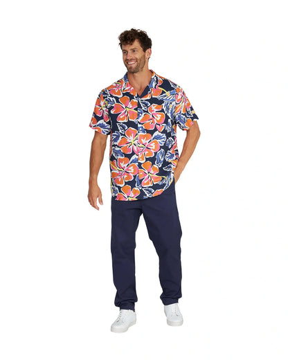 Full body view of a male model wearing the Okanui Rhapsody Aloha Short Sleeve Shirt in navy multi, navy pants and white shoes.