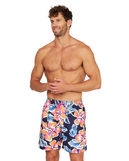 A fit male model wearing the Okanui Rhapsody Swim Short in navy multicolor in a slightly side view angle.