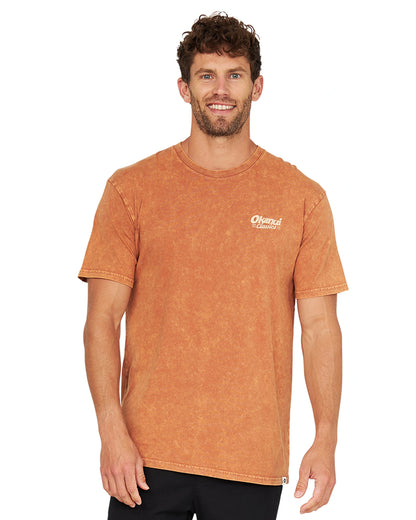 Closer front view of a male model wearing the Okanui Big Screen T-Shirt in rust color.