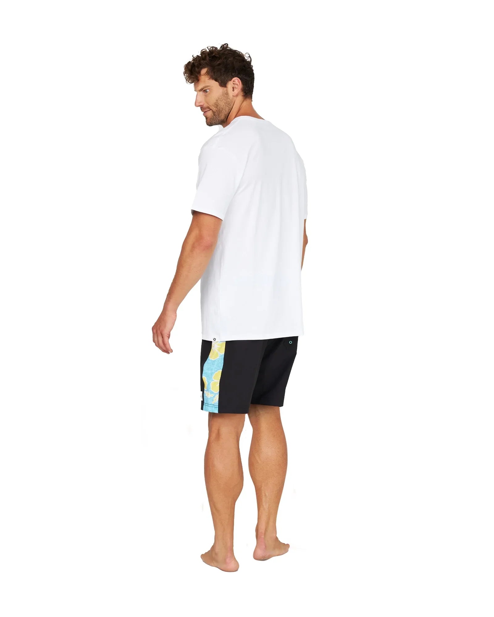 Back view of male model wearing the Okanui Sidelines Boardrider Boardshort in Black and a white t-shirt.