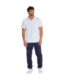 Full body front view of a male model wearing the Okanui Starboard Short Sleeve Shirt in Hibiscus white wearing navy pants and white shoes.