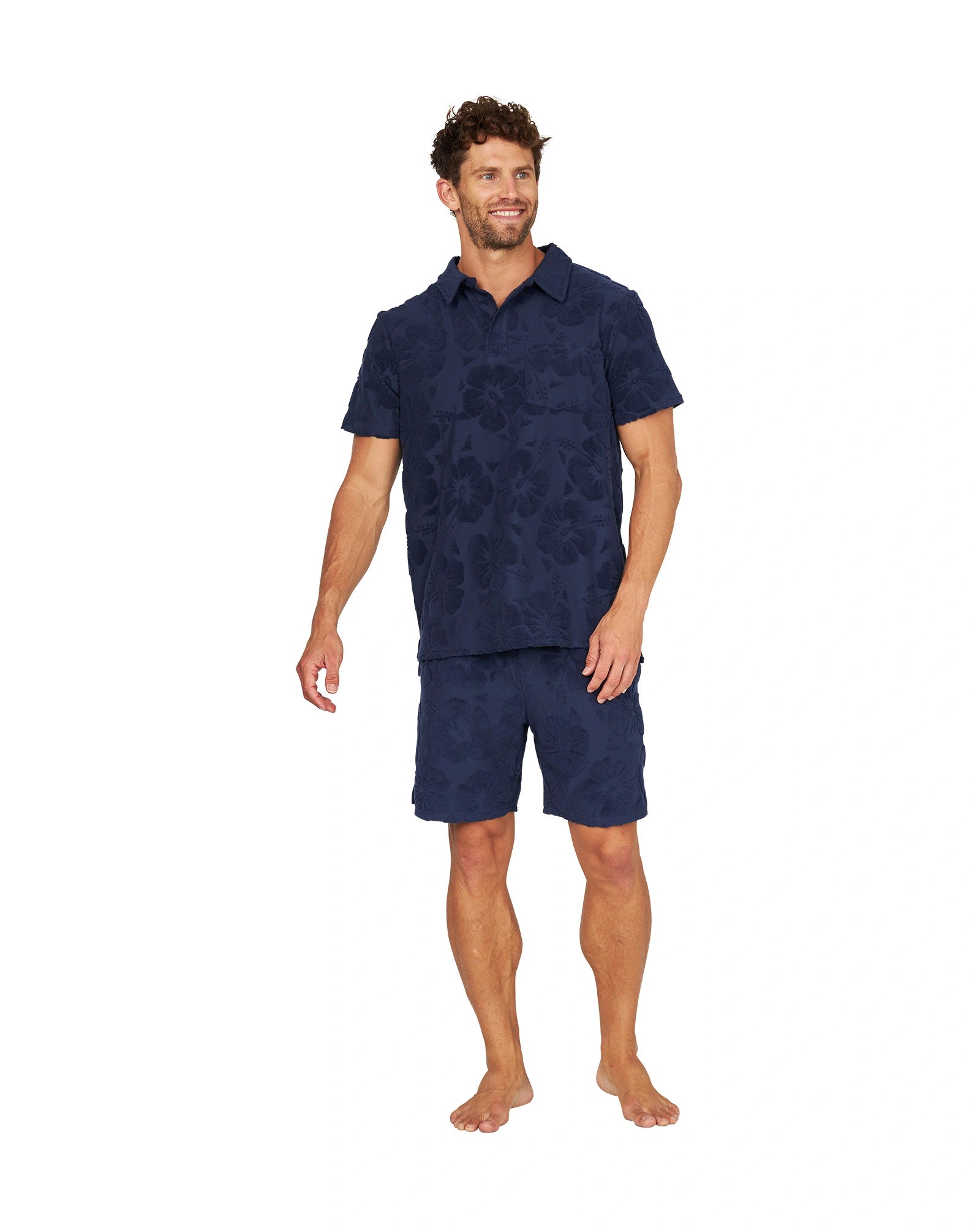 Full body view of male model wearing the Okanui Weekend Terry Jacquard Polo in Hibiscus Navy with terno shorts.