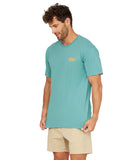 A side view of a model wearing the Okanui Big Screen T-Shirt in washed teal color with walkshorts.