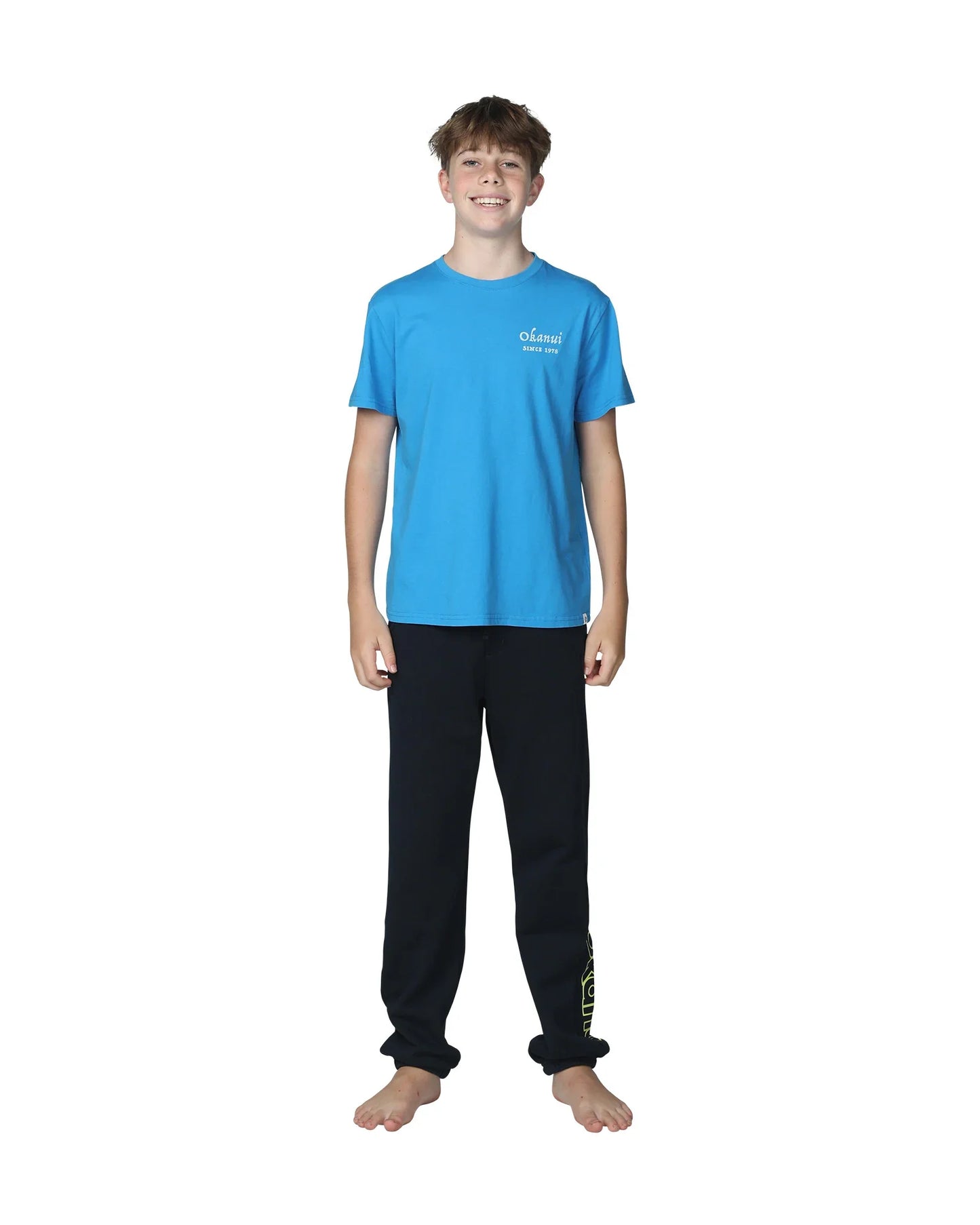 Full body front view of a boy wearing the Okanui Winter Keyline trackies for Kids in Navy color paired with a washed blue color Okanui T-shirt