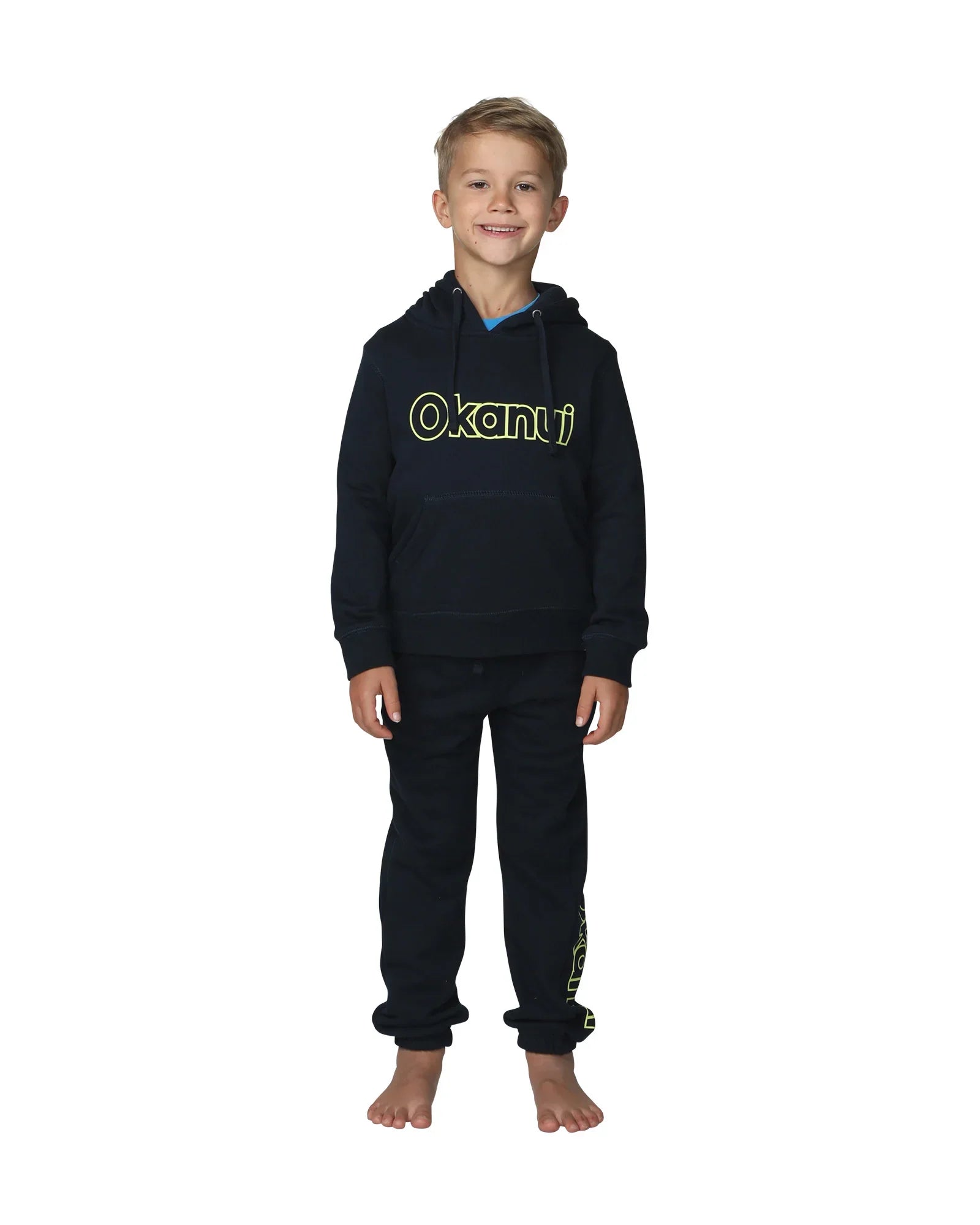 Full body front view of a little boy wearing the Okanui Winter Keyline trackies for Kids in Navy color paired with a Navy color Okanui jacket