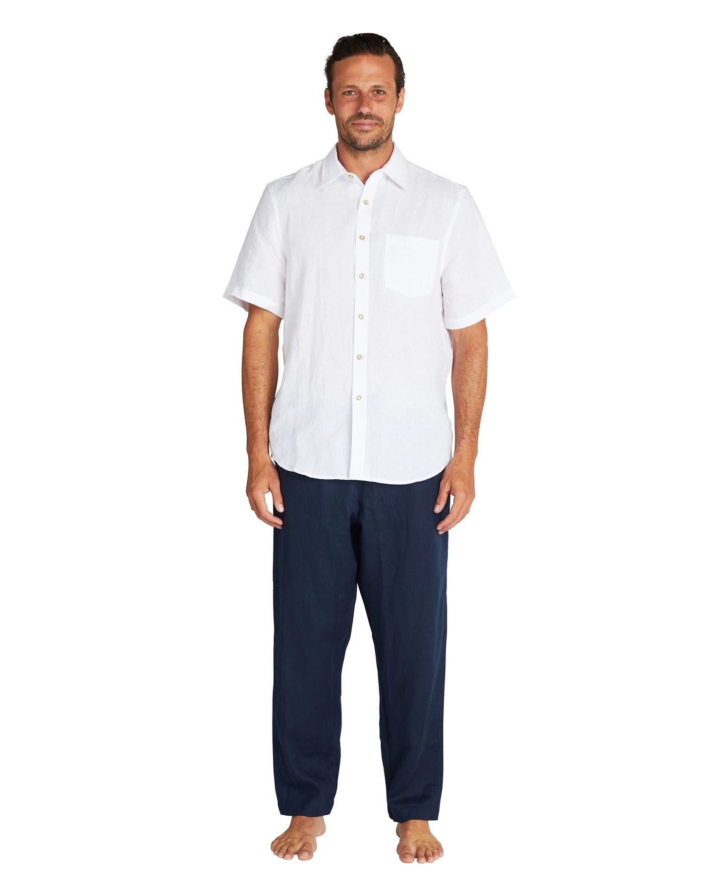 The Okanui linen pants in navy color is paired with a white short sleeve shirt.