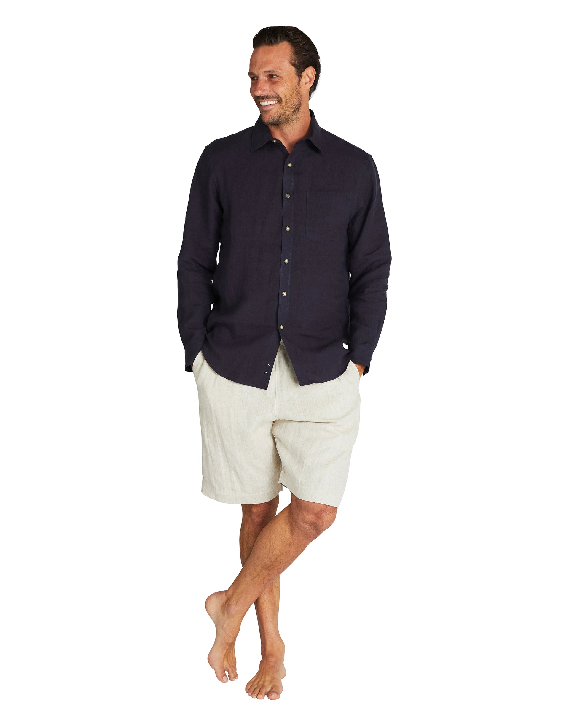 Male model wearing Okanui's linen long sleeve shirt in navy colour with linen shorts.