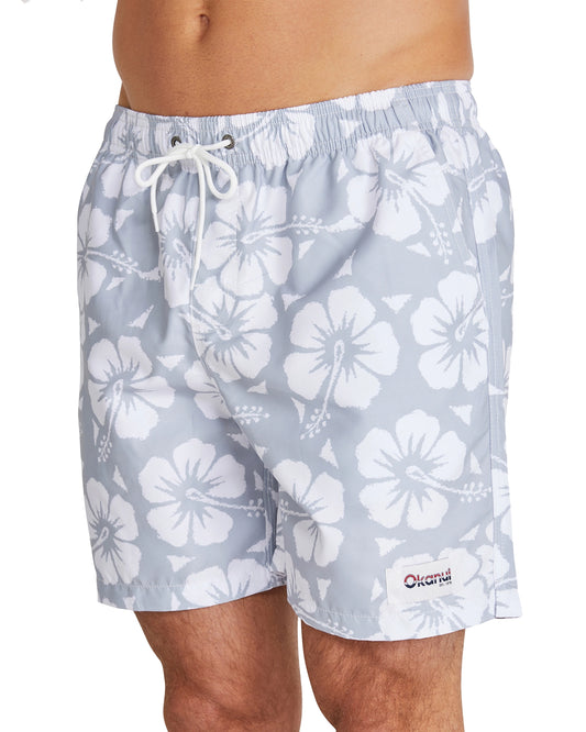 A close up view of the Okanui Classic Swim Shorts with the signature Hibiscus flower print pattern and the Okanui patch on the bottom left part of the shorts.